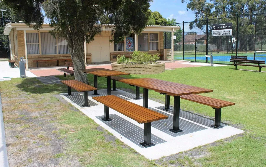 New picnic tables in front of the brick clubhouse at Burden Park