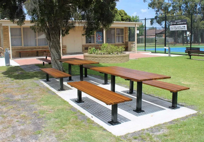 New picnic tables in front of the brick clubhouse at Burden Park Tennis Club.
