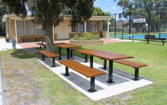 Picnic tables in front of the brick clubhouse at Burden Park