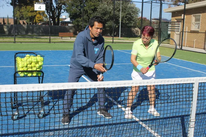 Coach Tuan Nguyen giving an adult member a private lesson at the net
