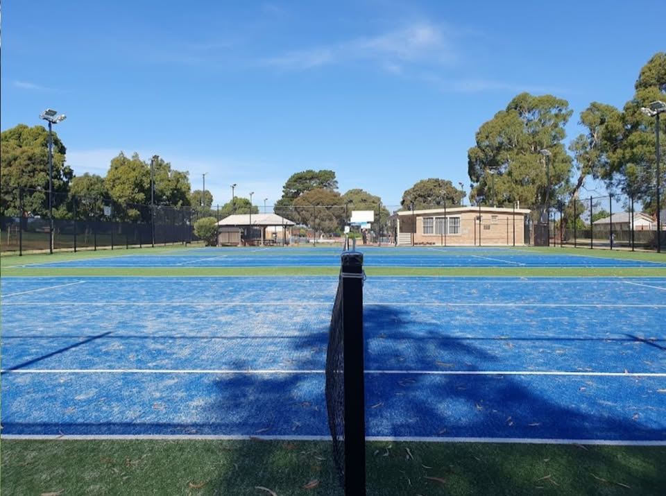 Ground-level view across Burden Park's courts to the clubhouse