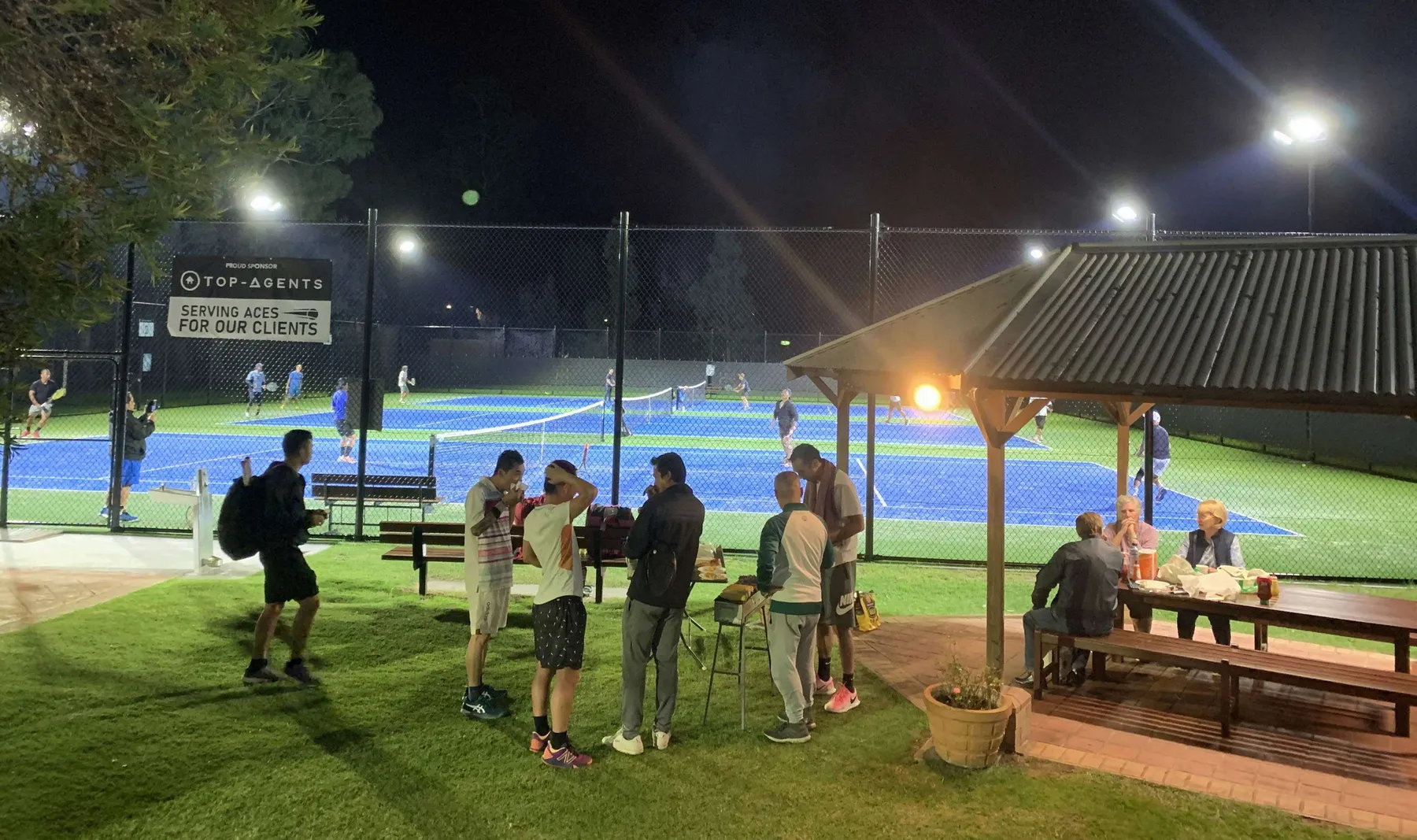 Floodlit mod-grass courts at Burden Park during a social tennis and BBQ night